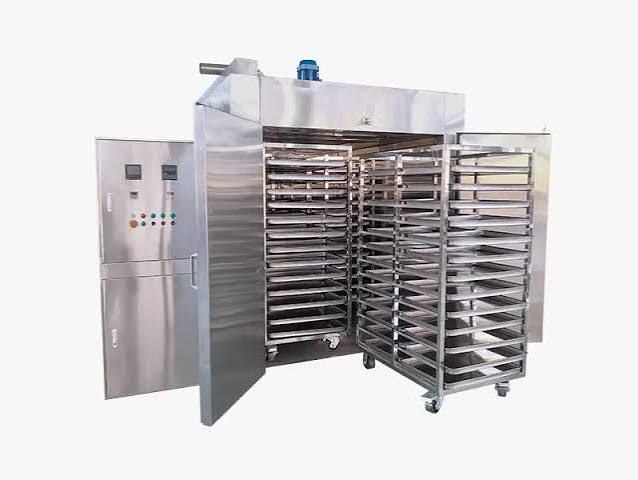 Representative image of an industrial drying oven with tray trolleys and temperature control panel
